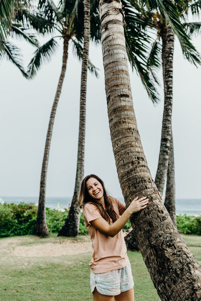 woman smiling while holding onto tree