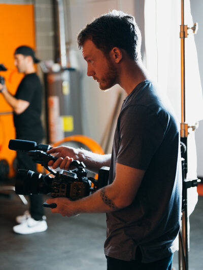 A videographer adjusting a camera rig on set, carefully preparing to capture high-quality footage. This image highlights the professionalism and technical expertise involved in video content creation at Future Fox Media, Denver, Colorado.