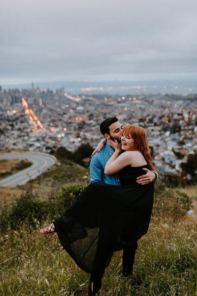 man holding woman with city in background