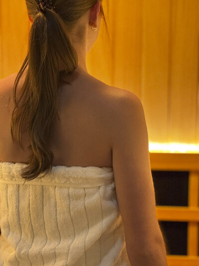 woman in white towel with back to camera in front of an infrared sauna