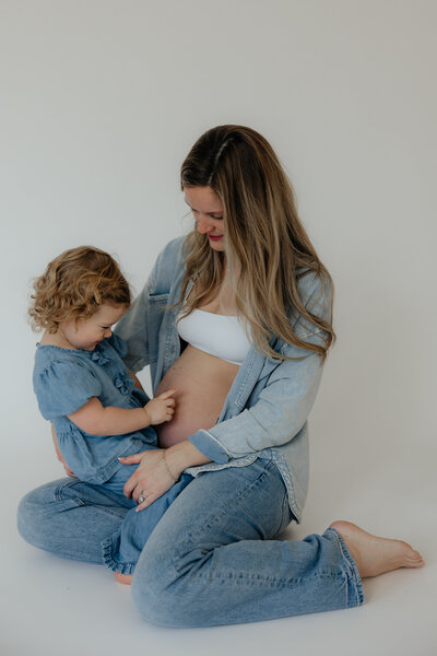 man and woman kissing holding pregnant belly