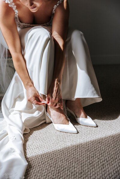 Bride putting on white shoes