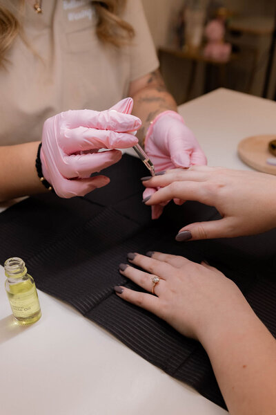 Pink gloves, client getting nails painted, applying cuticle oil