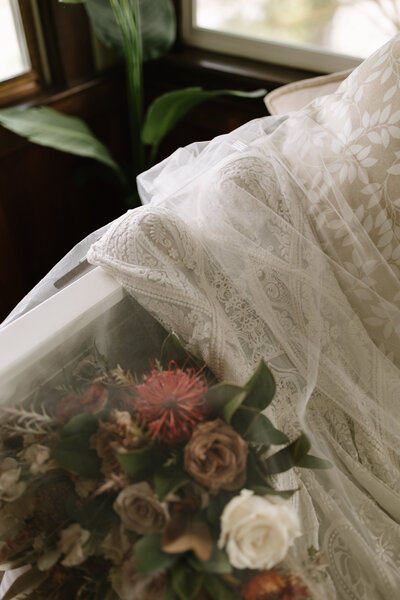 Wedding dress draped over couch with veil and bouquet by elopement photographer washington Erica Rochelle photography