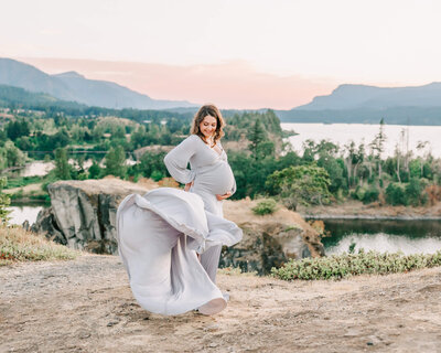 silver dress family photography session with mom holding belly with dress flowing in the wind outside of portland oregon