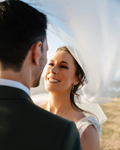 Bride smiling at groom beneath her flowing veil during golden hour at a TPC Summerlin Wedding