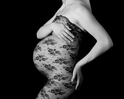 Pregnant woman celebrates her pregnancy in lace body wrap during maternity photography session