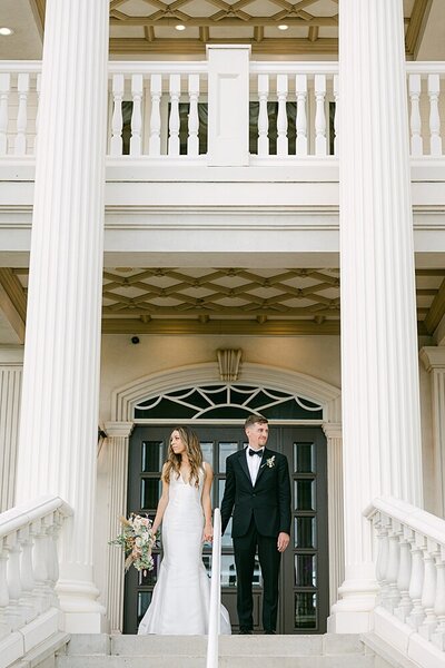 bride and groom posed in between columns