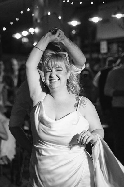 Bride smiling and dancing during a lively Perth wedding reception under string lights.