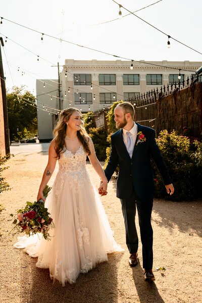 a bride and groom walking hand in hand down a alley way in downtown abilene, texas looking at each other laughing while Shelly Voss documents their wedding.
