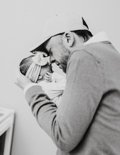 New dad holds his newborn as she cries