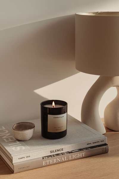 A stack of books, a candle, and an organic shaped lamp vignette