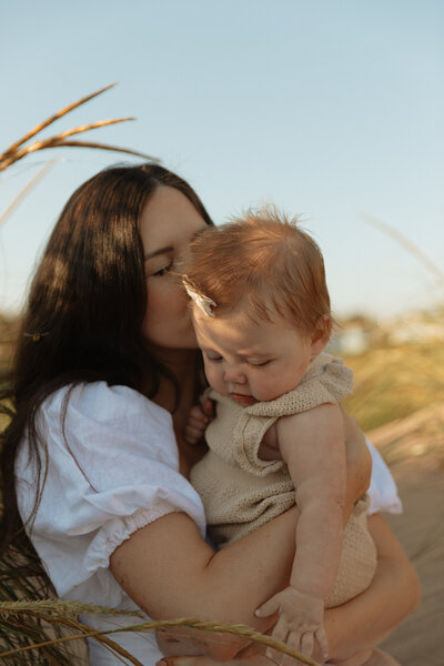 mom kisses baby on beach in pei
