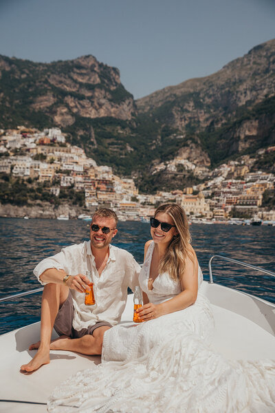 couple pose on boat with Positano in the background