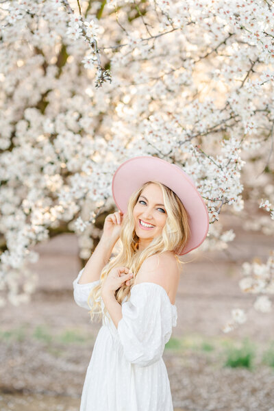 Bay area photographer, Amber Courtney, stands smiling in a field with glowing, golden hour light.