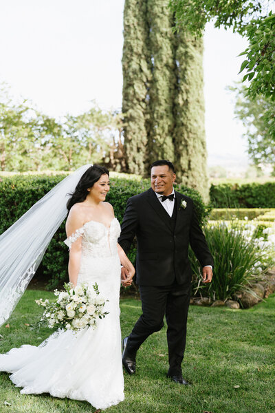 Bride and groom at black tie wedding while holding hand at garre vineyard in livermore 