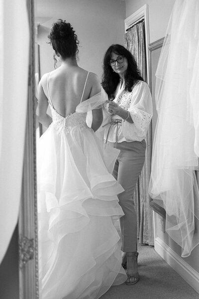 Bridal seamstress adjusting a layered tulle wedding gown on a bride during a custom dress fitting