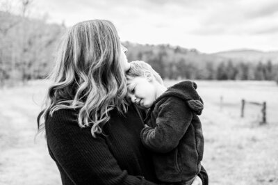 Black and white photo of a mother holding her child close in a quiet outdoor setting in Connecticut