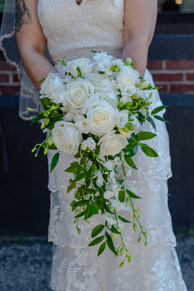 Bride holding white and green wedding bouquet with roses