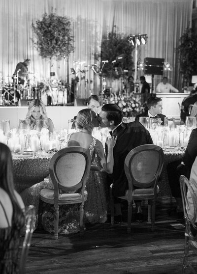 Wedding reception with the couple at a large head table, kissing