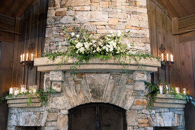 stone fireplace with greenery and florals sitting on mantle