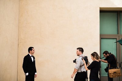 Groom poses before his wedding in front of a team of photographers