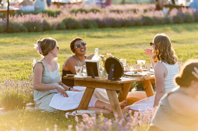 seated guests at a picnic laughing and eating food as part of a fundraiser.  Captured by Ottawa Event Photographer JEMMAN Photography COMMERCIAL