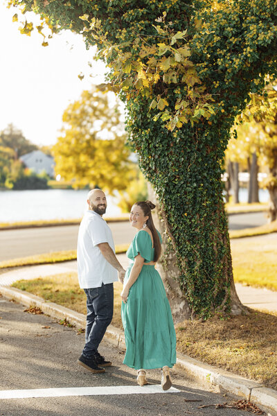 Spring Lake | Couple walking hand in hand among trees during engagement session | New Jersey