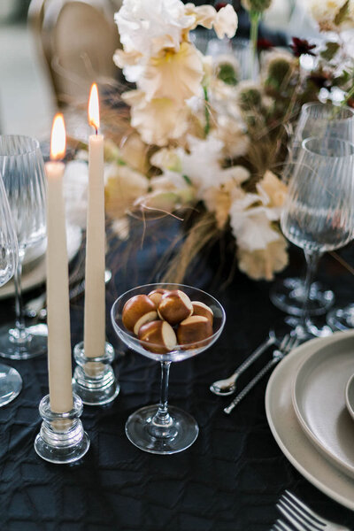 Modern and sophisticated dinner party table featuring candlelight, a black tablecloth, and modern Wave glassware