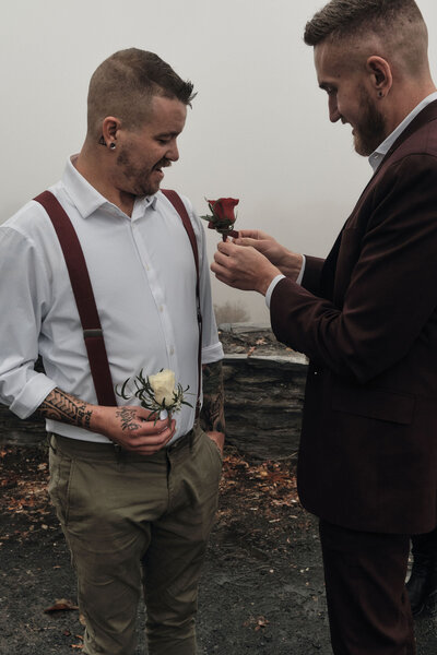 Eloping couple pinning flowers on each other during their wedding ceremony