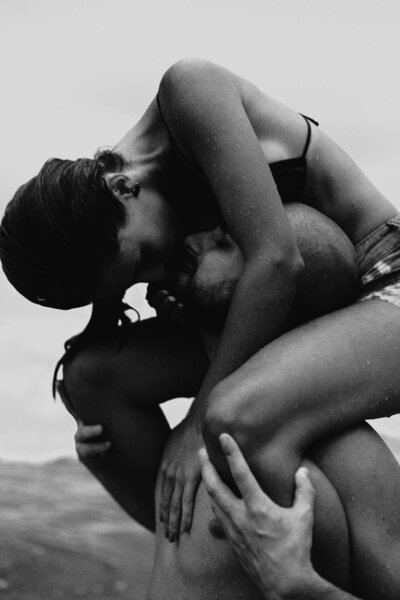 woman kissing man while sitting on his shoulders