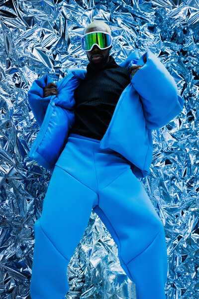 Man wearing a bright baby blue coat and pants with green sunglasses