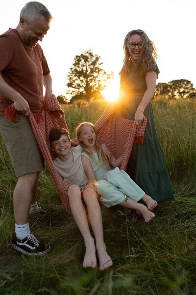 family outside sunset kids in blanket in field