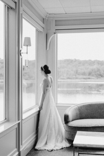 Bride sitting with groom standing behind her in black and white