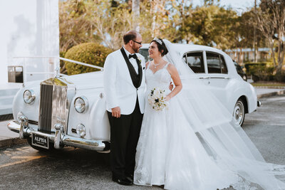 bride and groom smiling at each other while standing next to old car