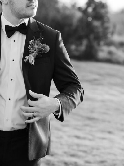 A groom tucks his hands into his pockets in a documentary wedding portrait.