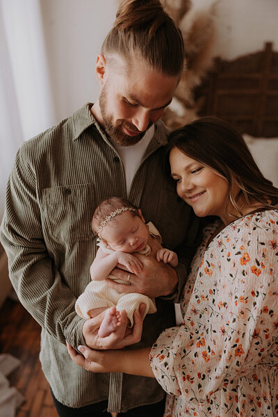 Newborn baby girl wearing a fall themed flower crown and wrapped in an orange blanket.