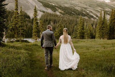 couple holding hands on the trail after hiking to their elopement ceremony