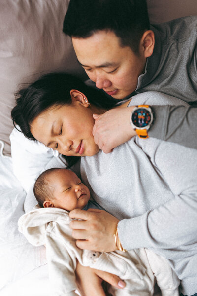 newborn being held in bed by a couple in their apartment in long island city 