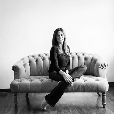 Gina Cooperman smiling on a tufted couch.