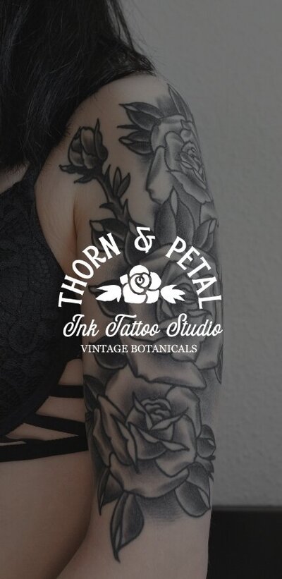 Girl in a black bra with a tattoo on her upper arm in the background with a white logo that reads "thorn and petal ink tattoo studio vintage botanicals" in the foreground