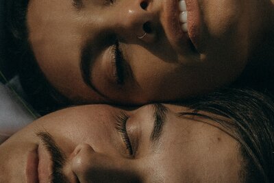 Close-up of bride and groom’s faces resting together in soft sunlight