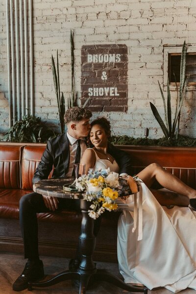 Chic and intimate wedding moment at Hotel Herringbone in Waco, featuring a bride and groom in love, cozying up in a moody, editorial-style setting.