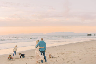 Family walking along the beach together on a peaceful morning with kids playing in the sand.