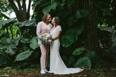 Lesbian Brides posing for portraits in front of lush greenery on their Elopement Day in New England.