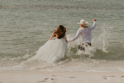 Bride and groom jumping into navarre beach after their ceremonyElopement-photographer-micro-wedding-destination-photographer-couples-picture