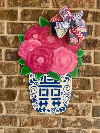 Pink flowers in white and blue Chinoiserie jar against tan brick background