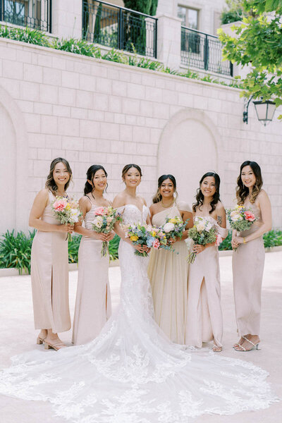 Bride in lace gown with bridesmaids holding colorful bouquets, captured by Toronto fine art wedding photographer