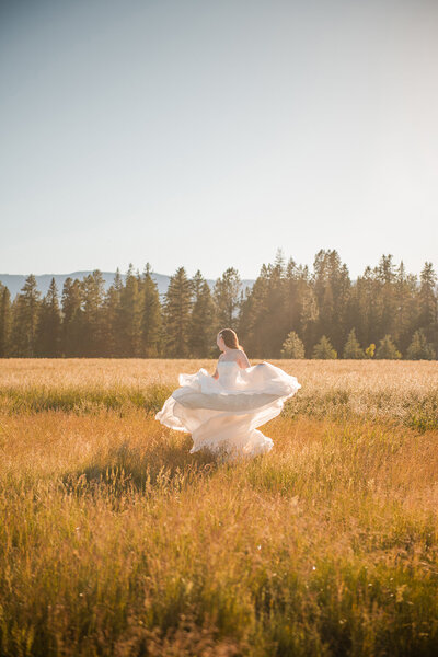 A happy bride twirls in a golden field in her wedding dress in Montana.