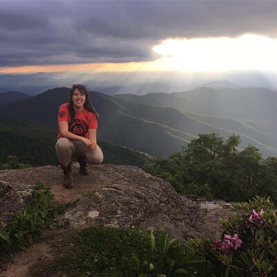 woman smiling sitting on top of a mountain